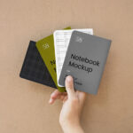 Top View of a Hand Holding Four A5 Notebook Cover Mockup