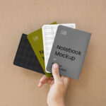 Top View of a Hand Holding Four A5 Notebook Cover Mockup