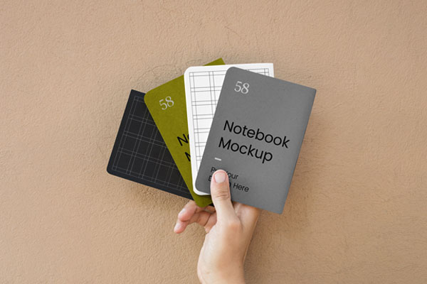 Top View of a Hand Holding Four A5 Notebook Cover Mockup