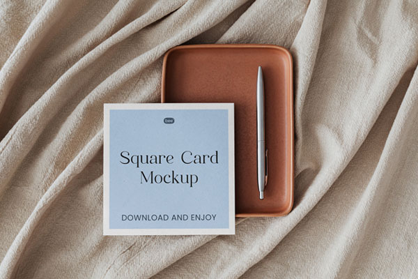 Top View of Square Card Mockup with Pen on Fabric